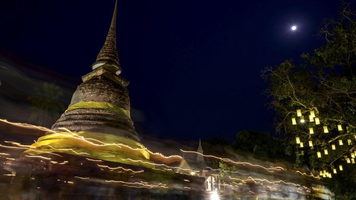A long exposure photograph shows Buddhist monks leading a candlelight procession around Wat Traphang Thong to celebrate Makha Bucha Day in Sukhotai on February 26, 2021. Mladen ANTONOV / AFP