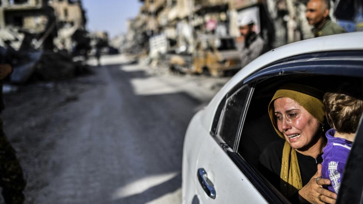 woman cries as she looks at her house in Raqa