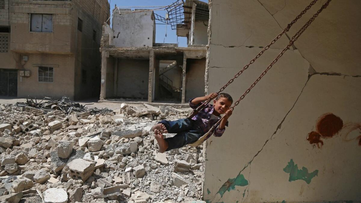 Syrian boy plays on a swing in a destroyed building