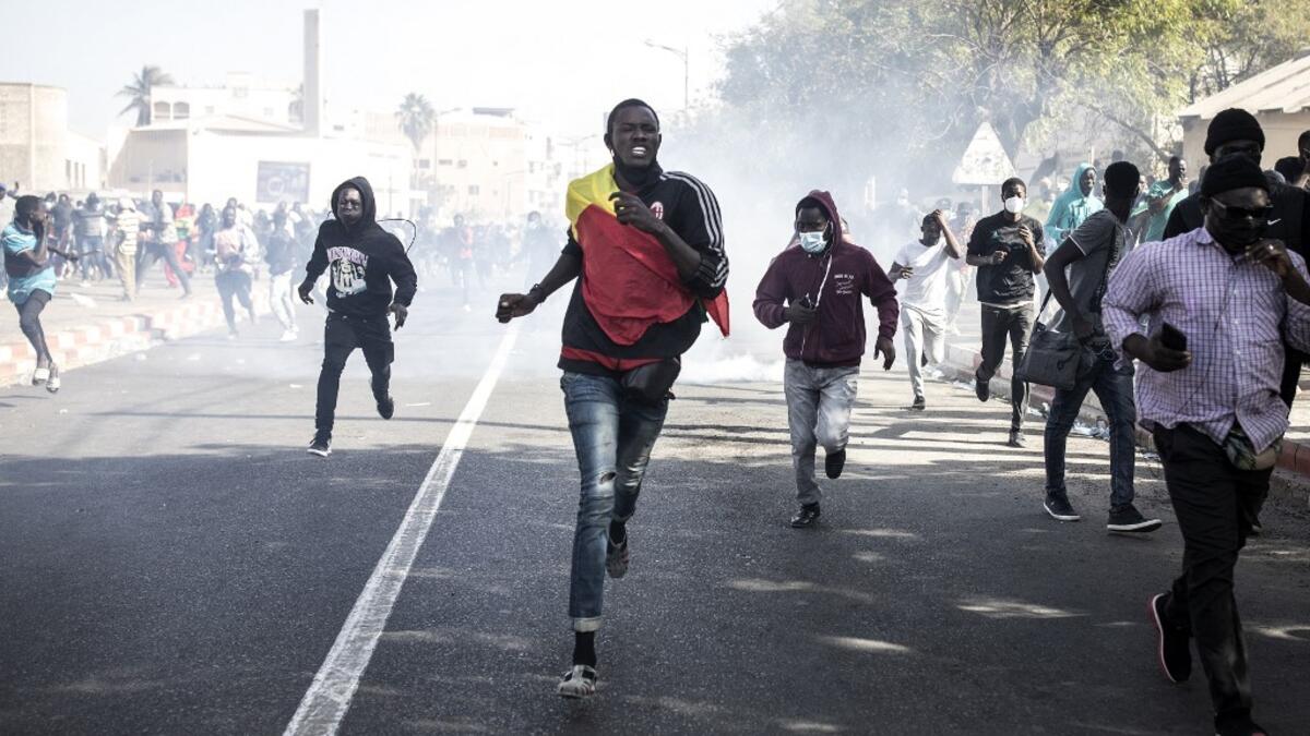 Protesters run from teargas during a protest in Dakar on March 8, 2021, after the country's opposition leader Ousmane Sonko was charged with rape. Usually considered a beacon of stability in a volatile region, deadly clashes between opposition supporters and security forces have rocked the West African state. JOHN WESSELS / AFP