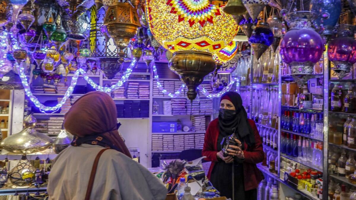 Women talk to a Palestinian shopkeeper selling Ramadan lanterns