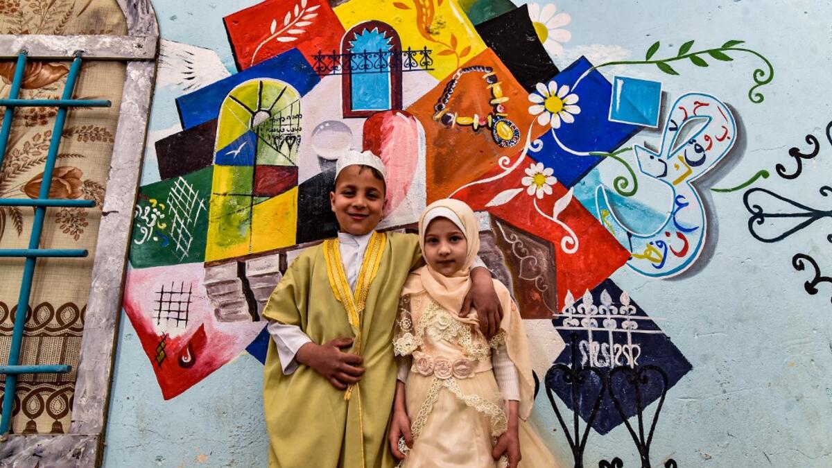 Children pose for a photo in front of a large graffiti depicting cultural elements including mosques