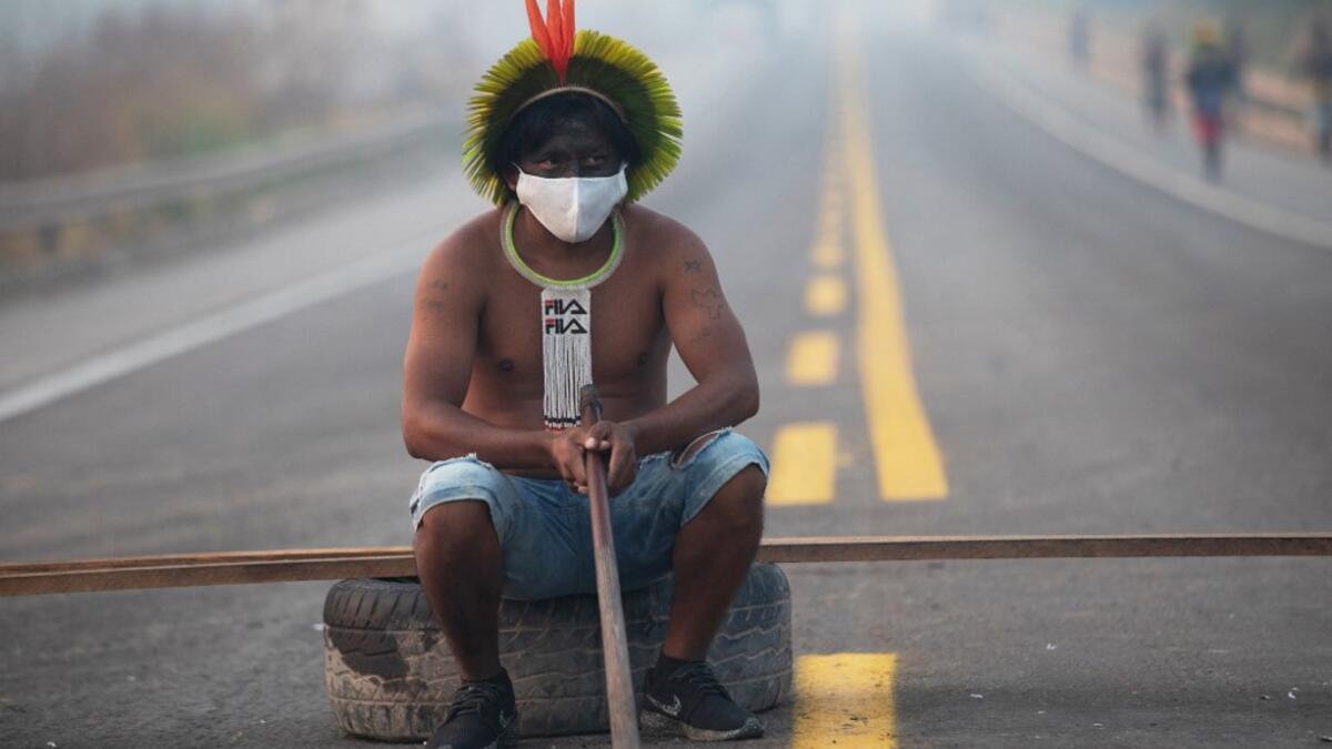 In this file photo taken on August 18, 2020 a member of the Kayapo tribe sits after they blocked highway BR163 during a protest on the outskirts of Novo Progresso in Para State, Brazil