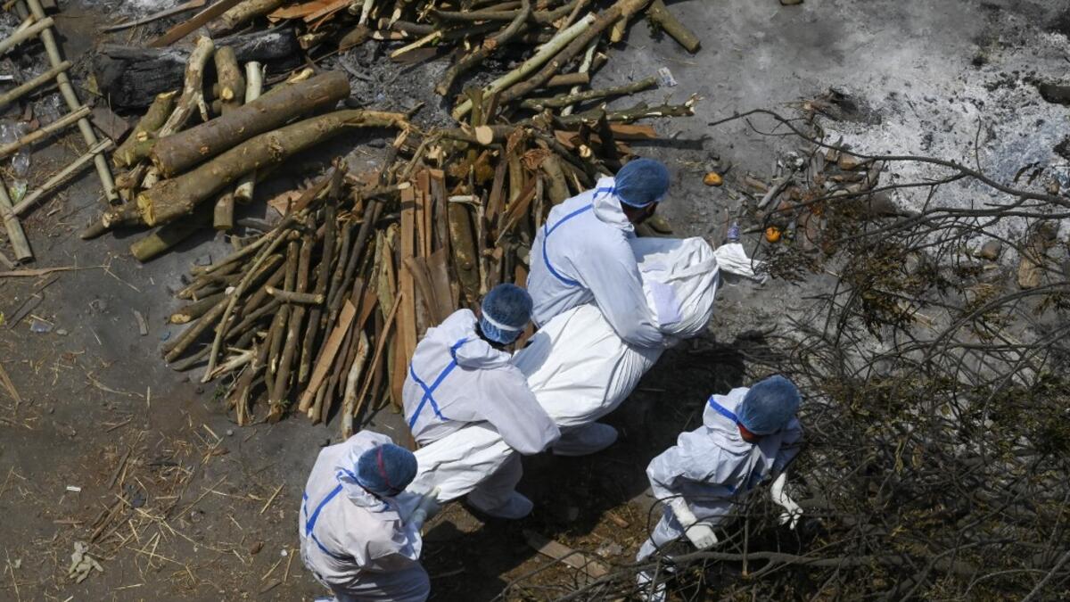 Family members and ambulance workers in PPE kit carry the body of a victim who died of the Covid-19