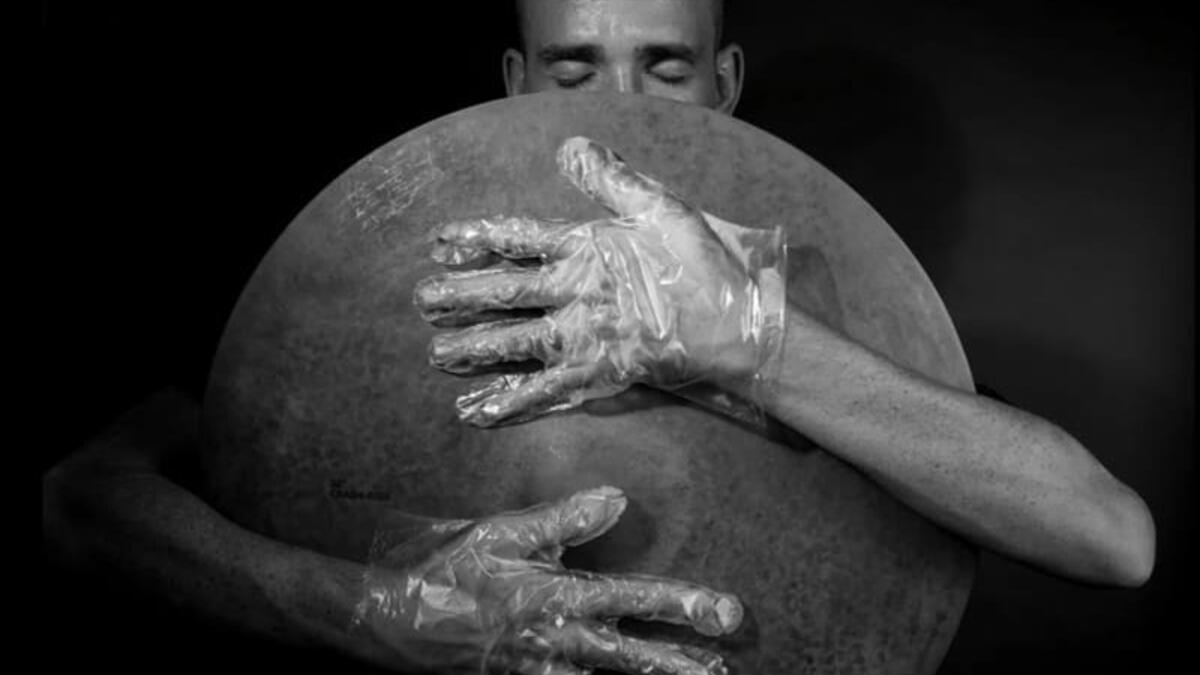 The musician in foil gloves is holding the instrument