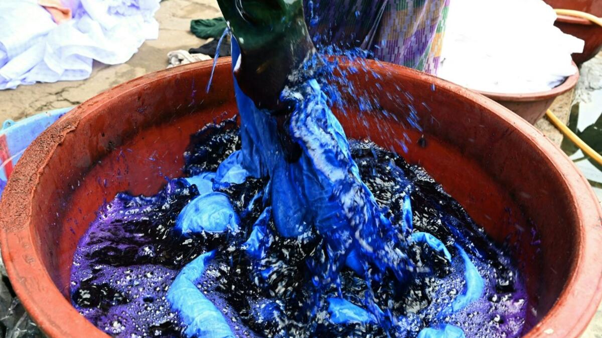 Dyers dye cotton fabric at Pathe'O house in the popular district of Treichville in Abidjan on March 31, 2021. A small self-taught tailor in his early years, the Ivorian-Burkinabe Pathe'O became the designer of African heads of state and celebrates the fiftieth anniversary of his brand, leading the "fight" for the recognition of fashion on the continent