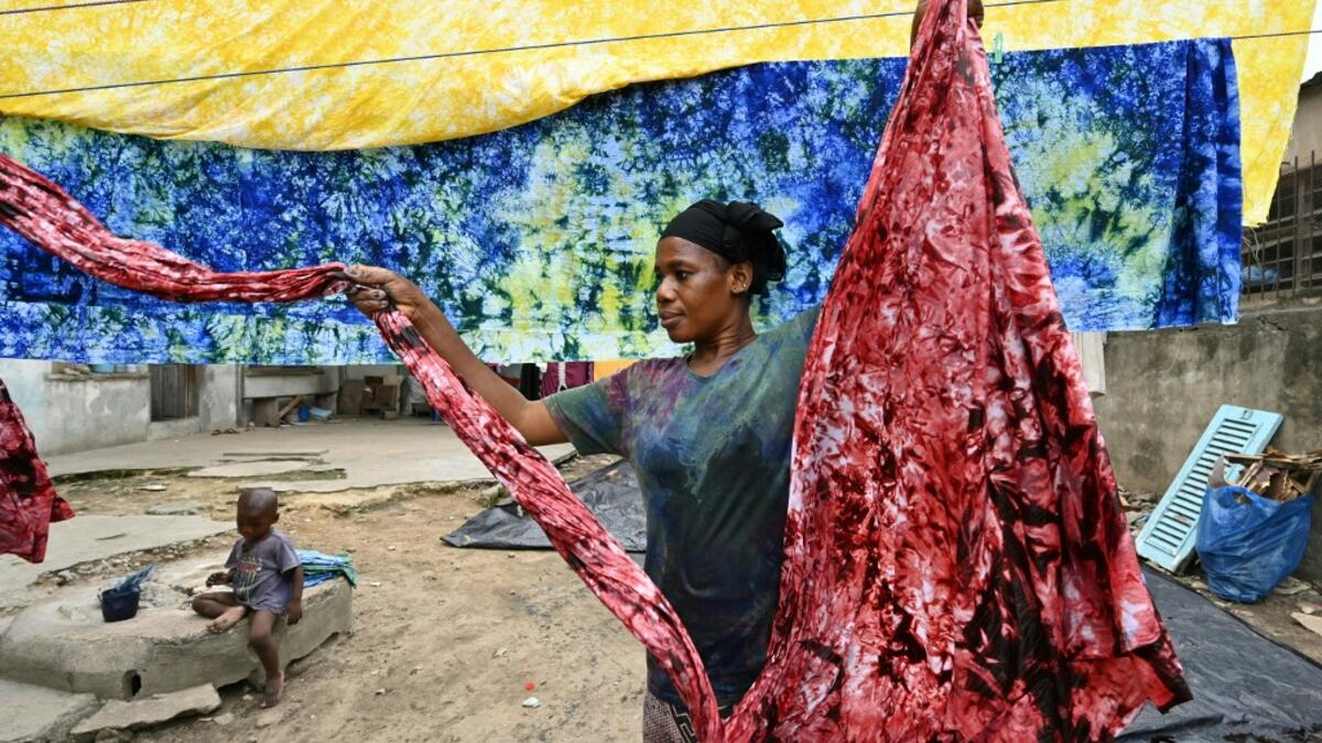 Dyers dye cotton fabric at Pathe'O house in the popular district of Treichville in Abidjan on March 31, 2021. A small self-taught tailor in his early years, the Ivorian-Burkinabe Pathe'O became the designer of African heads of state and celebrates the fiftieth anniversary of his brand, leading the "fight" for the recognition of fashion on the continent.