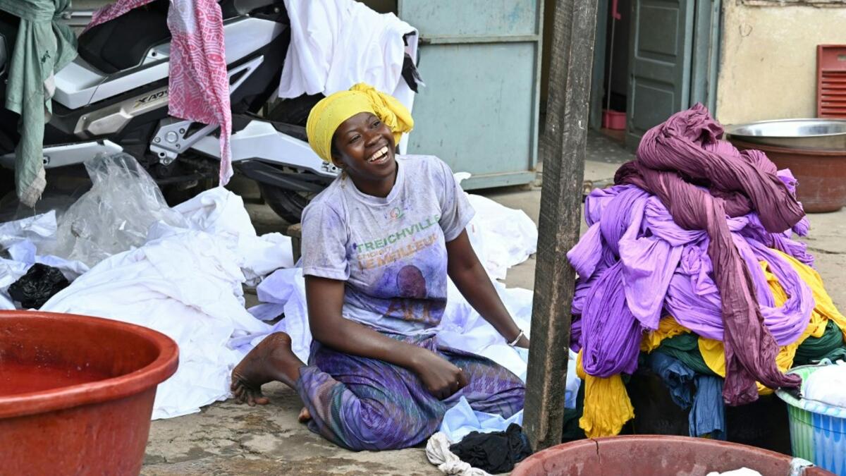 A dyer smiles as she poses for a photograph at Pathe'O house in the popular district of Treichville in Abidjan on March 31, 2021. A small self-taught tailor in his early years, the Ivorian-Burkinabe Pathe'O became the designer of African heads of state and celebrates the fiftieth anniversary of his brand, leading the "fight" for the recognition of fashion on the continent