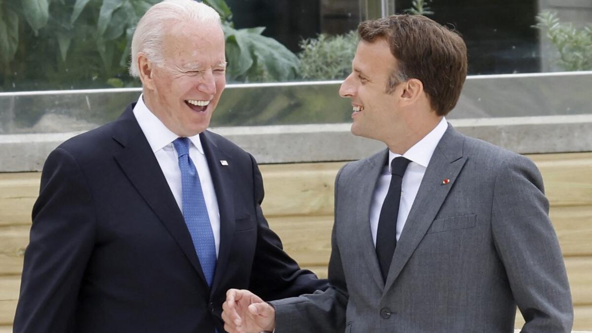 US President Joe Biden (L) and France's President Emmanuel Macron share a light moment before the family photo at the start of the G7 summit in Carbis Bay, Cornwall on June 11, 2021. G7 leaders from Canada, France, Germany, Italy, Japan, the UK and the United States meet this weekend for the first time in nearly two years, for three-day talks in Carbis Bay, Cornwall