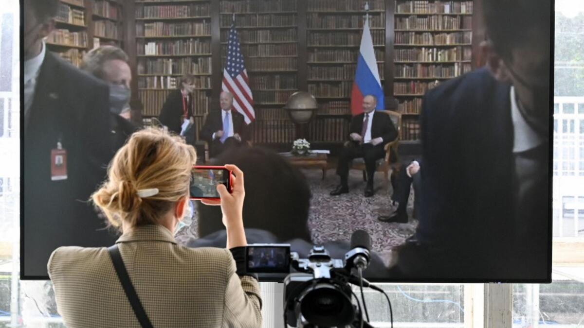 A journalist takes a picture of the screen displayed in the press room showing US President Joe Biden and Russian President Vladimir Putin during the US-Russia summit at the Villa La Grange, in Geneva