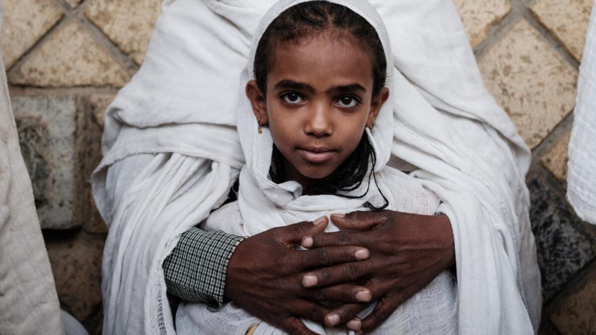 An 8-year-old girl Ethiopian Orthodox devote is held by her father as they attend the Saint Michael's anniversary celebration at St. Michael church in Mekele, the capital of Tigray region, Ethiopia