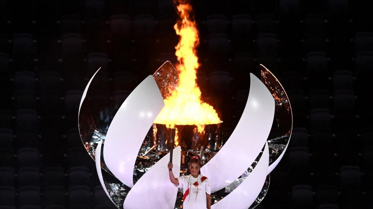 Japanese tennis player Naomi Osaka holds the Olympic Torch after lighting the flame of hope in the Olympic Cauldron during the opening ceremony of the Tokyo 2020 Olympic Games, at the Olympic Stadium, in Tokyo