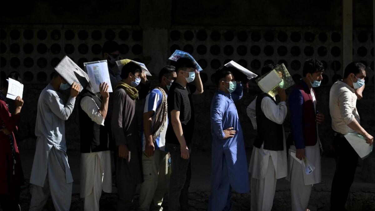 People stand in a queue to submit their passport applications at an office in Kabul on July 25, 2021. Dozens begin lining up at the passport office in Kabul before dawn most days, and by eight in the morning the queue already stretches for a good hundred metres.