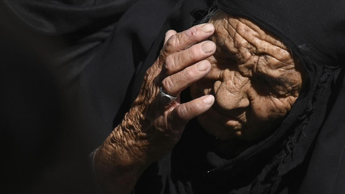 An elderly woman reacts as she sits in a queue along with others to submit their passport applications at an office in Kabul on July 25, 2021. Dozens begin lining up at the passport office in Kabul before dawn most days, and by eight in the morning the queue already stretches for a good hundred metres.