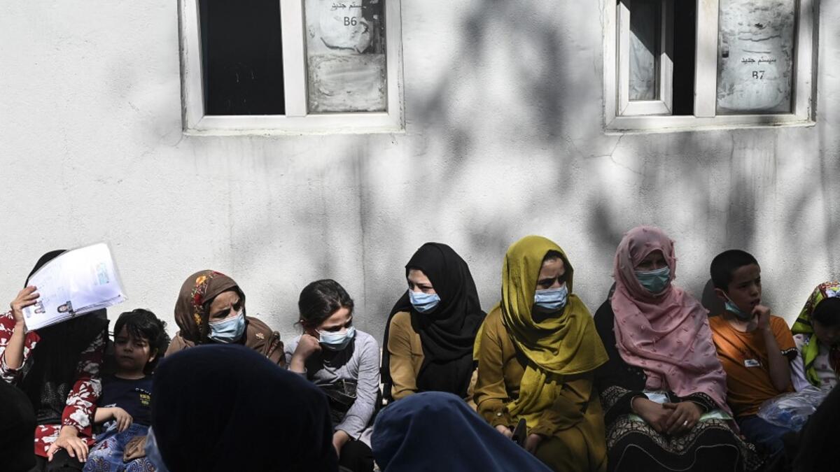 People sit in a queue to submit their passport applications at an office in Kabul on July 25, 2021. Dozens begin lining up at the passport office in Kabul before dawn most days, and by eight in the morning the queue already stretches for a good hundred metres.