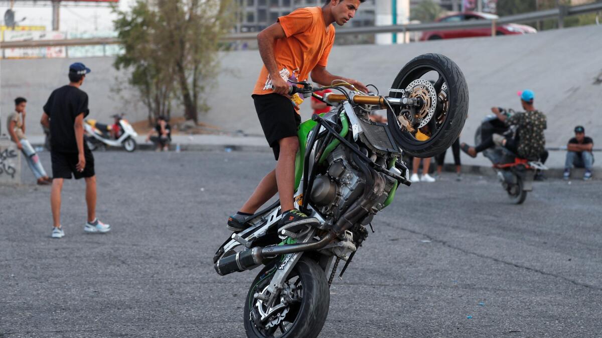 Iraqi youths perform stunts on motorbikes and scooters in the Jadriya district of Baghdad on August 6, 2021. All dressed up and nowhere to go: many young Iraqis in Baghdad make an effort to be hip, even as they admit their country may have no future.