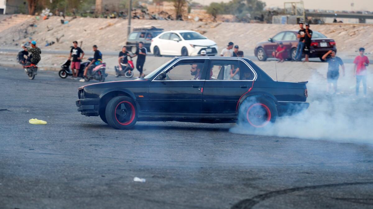 An Iraqi driver shows off his drifting skills as youths watch in the Jadriya district of Baghdad on August 6, 2021. All dressed up and nowhere to go: many young Iraqis in Baghdad make an effort to be hip, even as they admit their country may have no future.