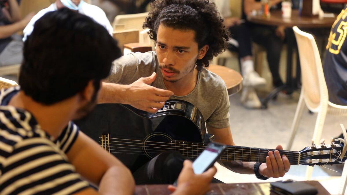 Iraqi guitarist Mohammed, 23, plays as he sits with his friends at a coffee shop in the Karrada district of the capital Baghdad, on August 6, 2021. All dressed up and nowhere to go: many young Iraqis in Baghdad make an effort to be hip, even as they admit their country may have no future.