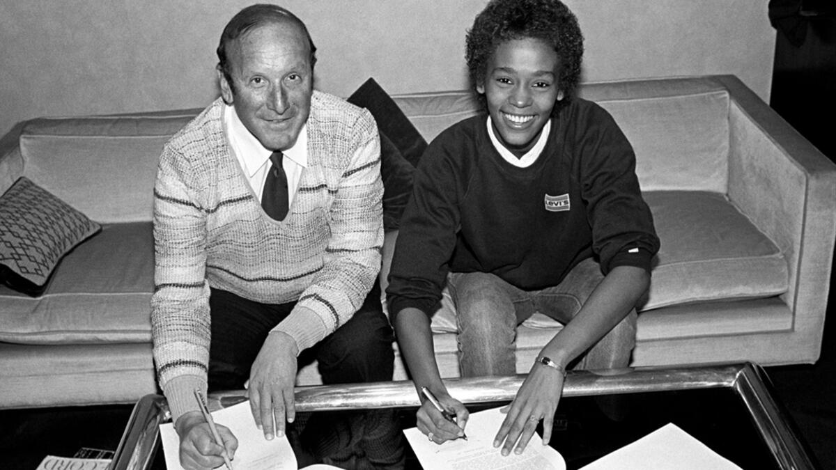 Whitney Houston signing her first recording contract alongside executive Clive Davis at Arista Records in New York City, April 1983