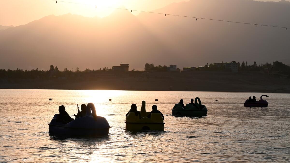 In this photograph taken on September 28, 2021 Taliban fighters ride on paddle boats at Qargha Lake on the outskirts of Kabul. "This is Afghanistan!" a Taliban fighter shouts on the pirate ship ride at a fairground in western Kabul, as his armed comrades cackle and whoop on board the rickety attraction. (Photo by WAKIL KOHSAR / AFP) / TO GO WITH: AFGHANISTAN-CONFLICT-FAIRGROUND, SCENE BY JAMES EDGAR - TO GO WITH: Afghanistan-conflict-fairground, SCENE by James EDGAR