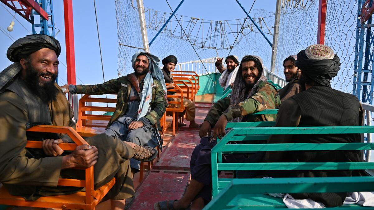 Taliban fighter shouts on the pirate ship ride at a fairground in western Kabul, as his armed comrades cackle and whoop on board the rickety attraction. (Photo by WAKIL KOHSAR / AFP) / TO GO WITH: AFGHANISTAN-CONFLICT-FAIRGROUND, SCENE BY JAMES EDGAR - TO GO WITH: Afghanistan-conflict-fairground, SCENE by James EDGAR