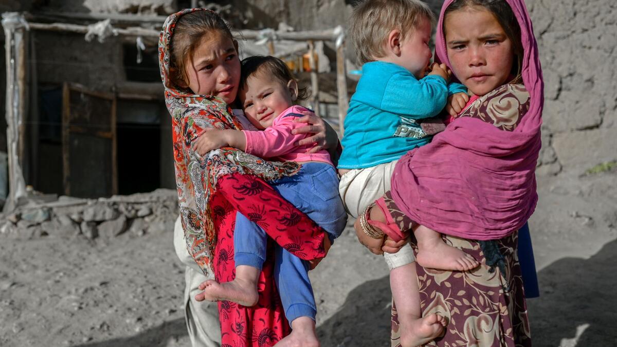In this picture taken on October 3, 2021, Hazara ethnic children stand on a cliff pockmarked by caves where people still live as they did centuries ago in Bamiyan.