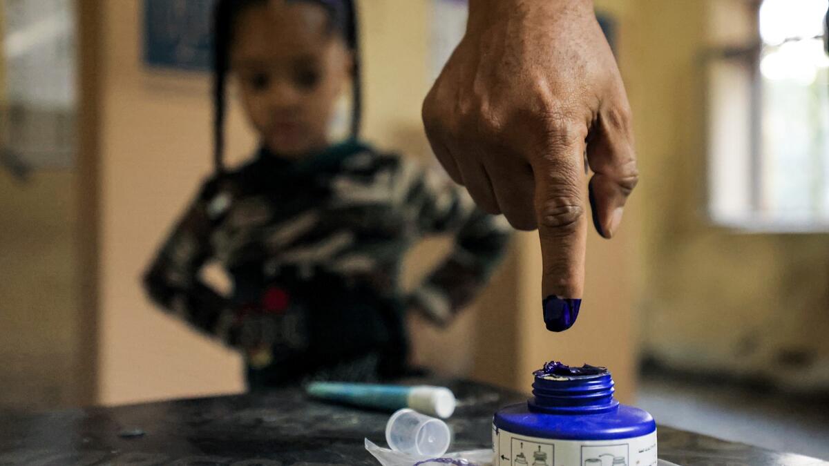 A man dips his finger in ink after voting at a polling station in Iraq's capital Baghdad during the early parliamentary elections on October 10, 2021. (Photo by AHMAD AL-RUBAYE / AFP)