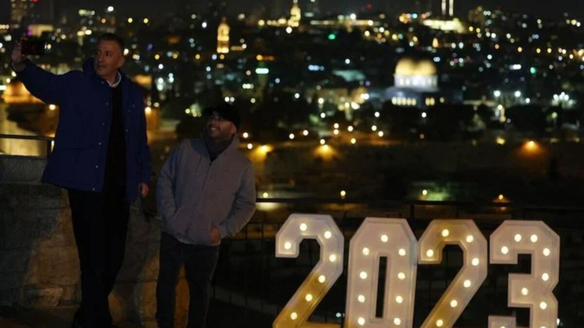 اشخاص يقفون لالتقاط صورة لافتة مضاءة 2023 في جبل الزيتون في القدس ، 31 ديسمبر 2022 (ا ف ب)