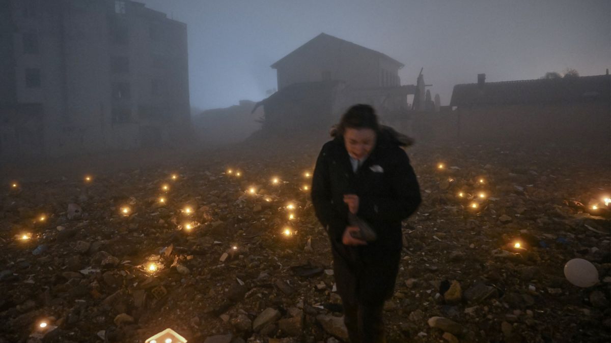 A woman leaves a candle at the site of a demolished building during the first anniversary of the earthquake, in Antakya on February 6, 2024. (Photo by Ozan KOSE / AFP) earthquake Turkey