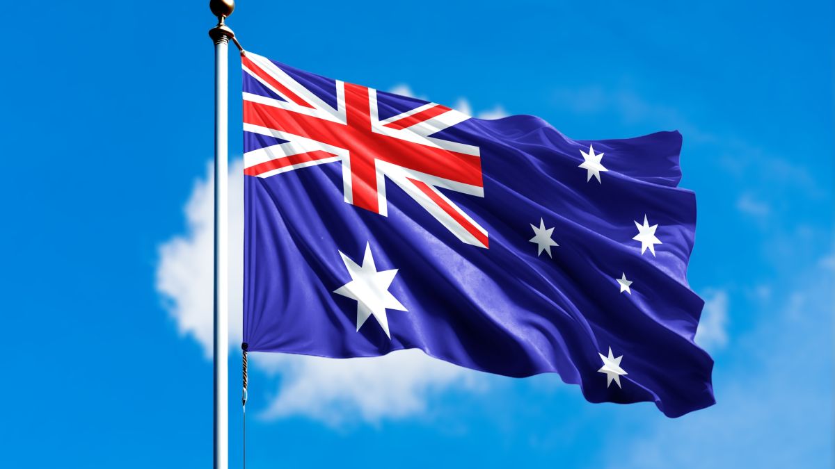 علم أستراليا يرفرف أمام خلفية زرقاء ضبابية من الغيوم.