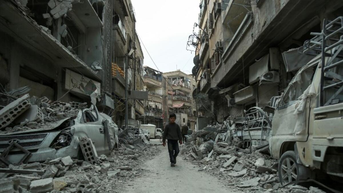 A picture taken on Mar. 8, 2018 shows a Syrian child walking down a street past rubble from destroyed buildings, in the rebel-held town of Douma in the Eastern Ghouta enclave on the outskirts of Damascus.  (HAMZA AL-AJWEH / AFP)