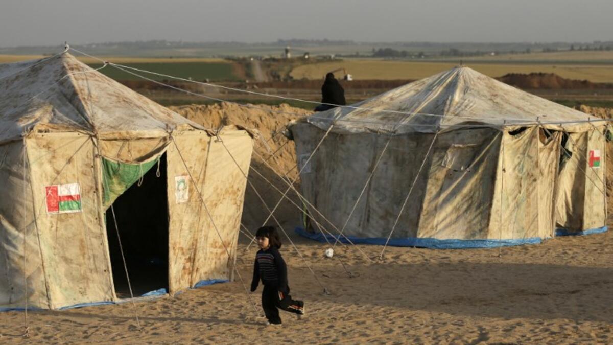 A girl runs next to tents pitched by Palestinians on the Gaza border with Israel (background), east of Jabalia, on Mar. 29, 2018, ahead of a six-week protest camp. The exceptional protest is dubbed "The Great March of Return" and has the backing of the Gaza Strip's Islamist rulers Hamas.
MAHMUD HAMS / AFP