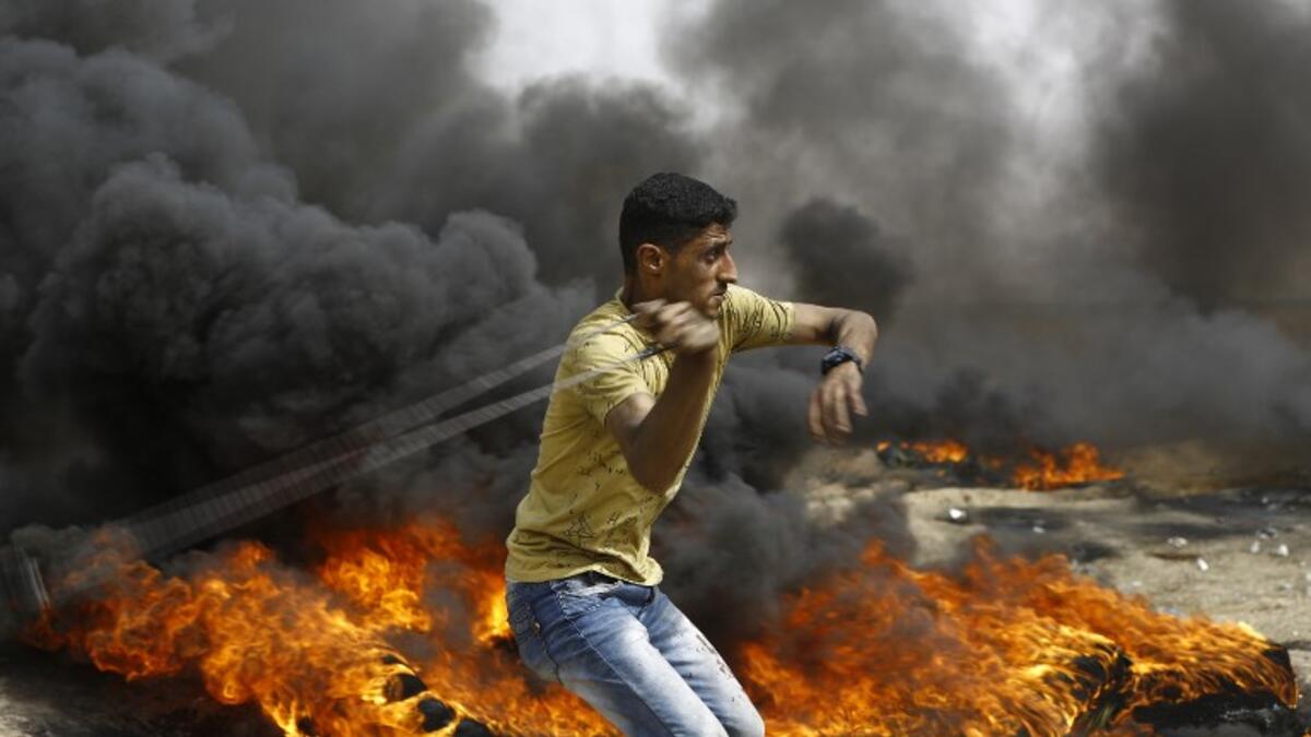 A Palestinian slings a shot by burning tires during clashes with Israeli forces across the border, following a demonstration calling for the right to return.
(MOHAMMED ABED / AFP)