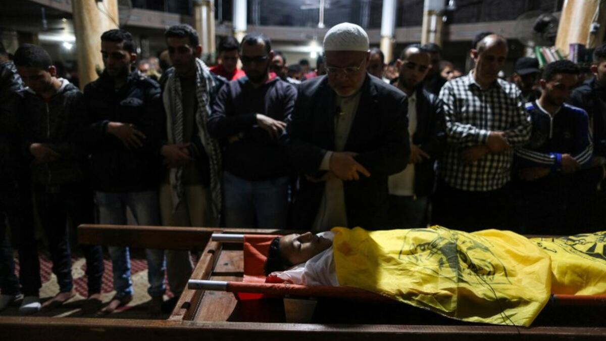 Relatives of 15-year-old Palestinian Mohammed Ibrahim Ayoub, who was shot and killed by Israeli security forces during clashes along the Israel-Gaza border, pray over his body during his funeral in Beit Lahia in the northern Gaza strip on April 20, 2018. (STRINGER / AFP)