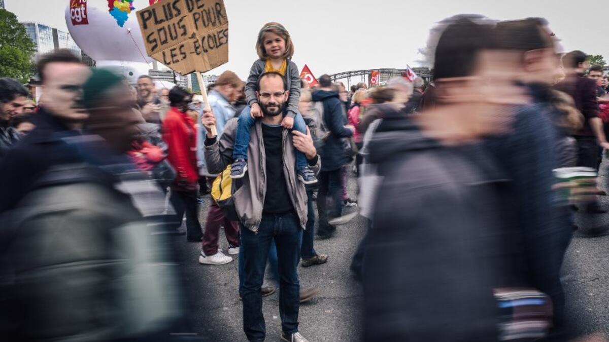 Pierre Gilbert, a 37 year old sociology university teacher, poses with his daughter during the annual May Day workers' rally in Paris on May 1, 2018 / AFP