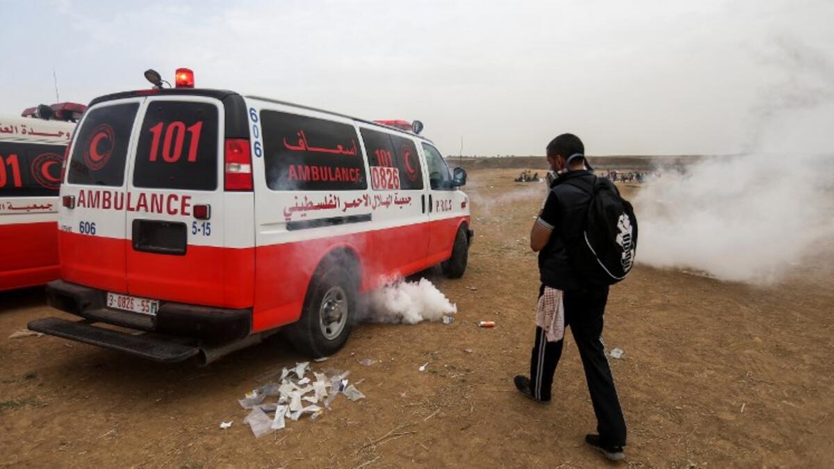 A Palestinian protester covers his face as he walks near an ambulance with incoming teargas canisters fired by Israeli forces during clashes following a demonstration near the border with the Gaza strip east of Jabalia on May 4, 2018, on the sixth straight Friday of mass demonstrations. (MOHAMMED ABED / AFP)