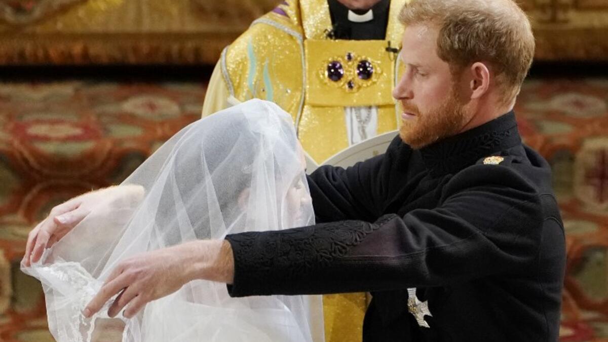 Britain's Prince Harry, Duke of Sussex (R) removes the veil of US actress Meghan Markle (L) as they stand at the altar together before Archbishop of Canterbury Justin Welby in St George's Chapel, Windsor Castle, in Windsor, on May 19, 2018 during their wedding ceremony. 
Owen Humphreys/ AFP
