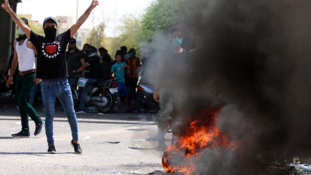 An Iraqi protester gestures near a burning tyre during a demonstration in Basra on July 15, 2018. (AFP/Haidar Mohammad Ali)