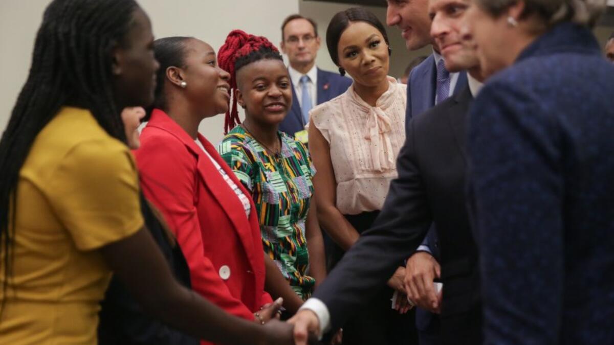 A woman reacts as British Prime Minister Theresa May (L), French President Emmanuel Macron (C) and Canadian Prime Minister Justin Trudeau (R) greet a group of women ahead the start of a Girl Education event at UN headquarters during the General Assembly of the United Nations in New York, September 25, 2018. 
AMR ALFIKY / AFP / POOL