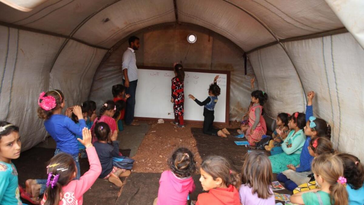 Syrian children who fled with their families from the northern countryside of Hama, attend a class at the makeshift school of "Zuhur al-Mustaqbal" (in Arabic "Flowers of the Future") in al-Jeneinah camp for displaced people in the village of Atme, in Syria's mostly rebel-held northern Idlib province, on October 1, 2018. Aaref WATAD / AFP