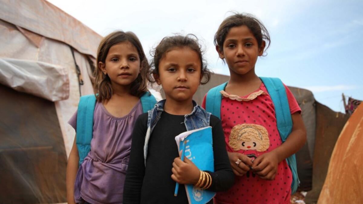 Syrian children who fled with their families from the northern countryside of Hama, pose in the yard of the makeshift school of "Zuhur al-Mustaqbal" (in Arabic "Flowers of the Future") in al-Jeneinah camp for displaced people in the village of Atme, in Syria's mostly rebel-held northern Idlib province, on October 1, 2018. Aaref WATAD / AFP
