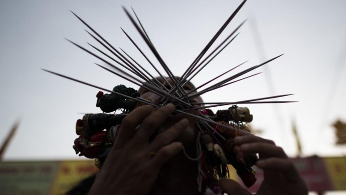 A devotee of the Loem Hu Thai Su shrine has multiple skewers pierced through his cheeks during the annual Vegetarian Festival in Phuket on October 12, 2018. Jewel SAMAD/AFP
