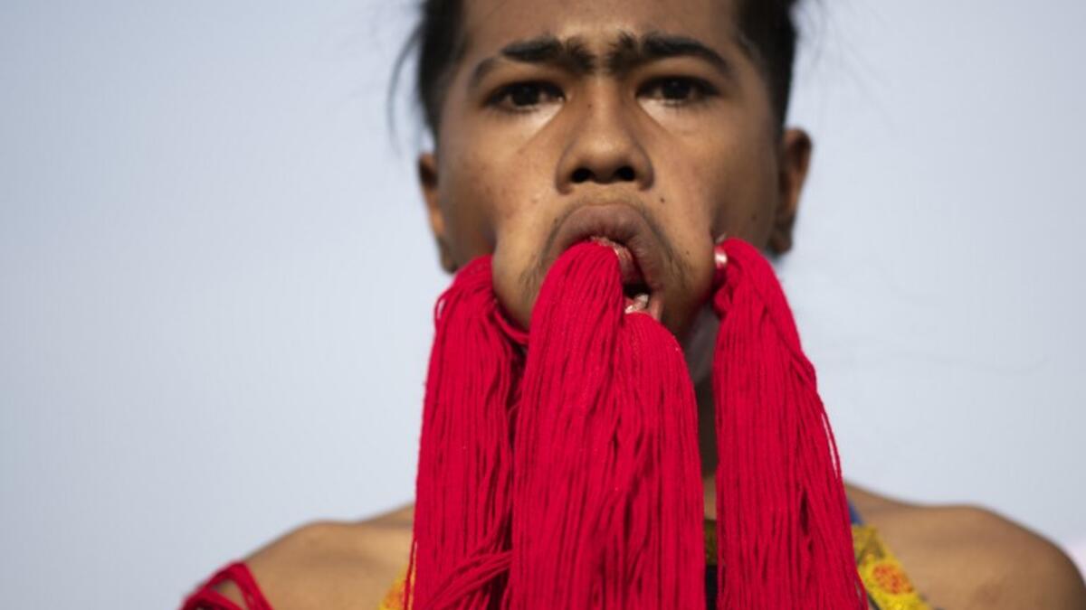 A devotee of the Loem Hu Thai Su shrine parades with coloured yarn through large piercings in his face during the annual Vegetarian Festival in Phuket on October 12, 2018. Jewel SAMAD/AFP