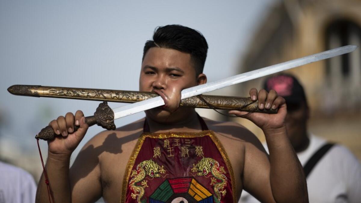 A devotee of the Loem Hu Thai Su shrine parades with a sword and a cover pierced through his cheek during the annual Vegetarian Festival in Phuket on October 12, 2018. Jewel SAMAD/AFP