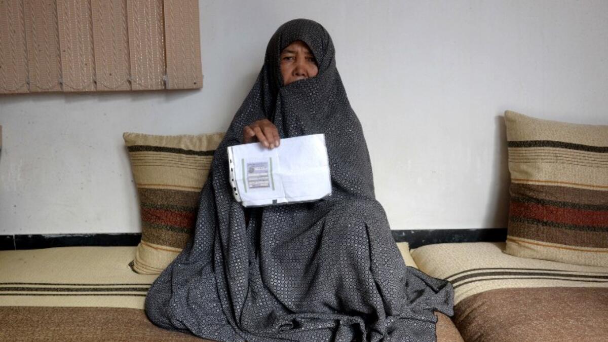 In this photo taken on October 11, 2018. Afghan housewife Fatimah, 55, poses for a picture as she holds her ID card or Tazkira registered to vote in the upcoming parliamentary election, at her House in Mazar-i-Sharif. 
FARSHAD USYAN / AFP