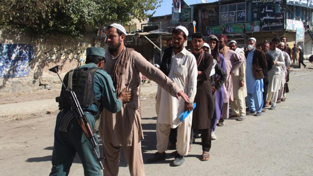 An Afghan policeman searches voters before casting their votes at a polling centre for the country's legislative election in Khost Province on October 20, 2018. 
FARID ZAHIR / AFP