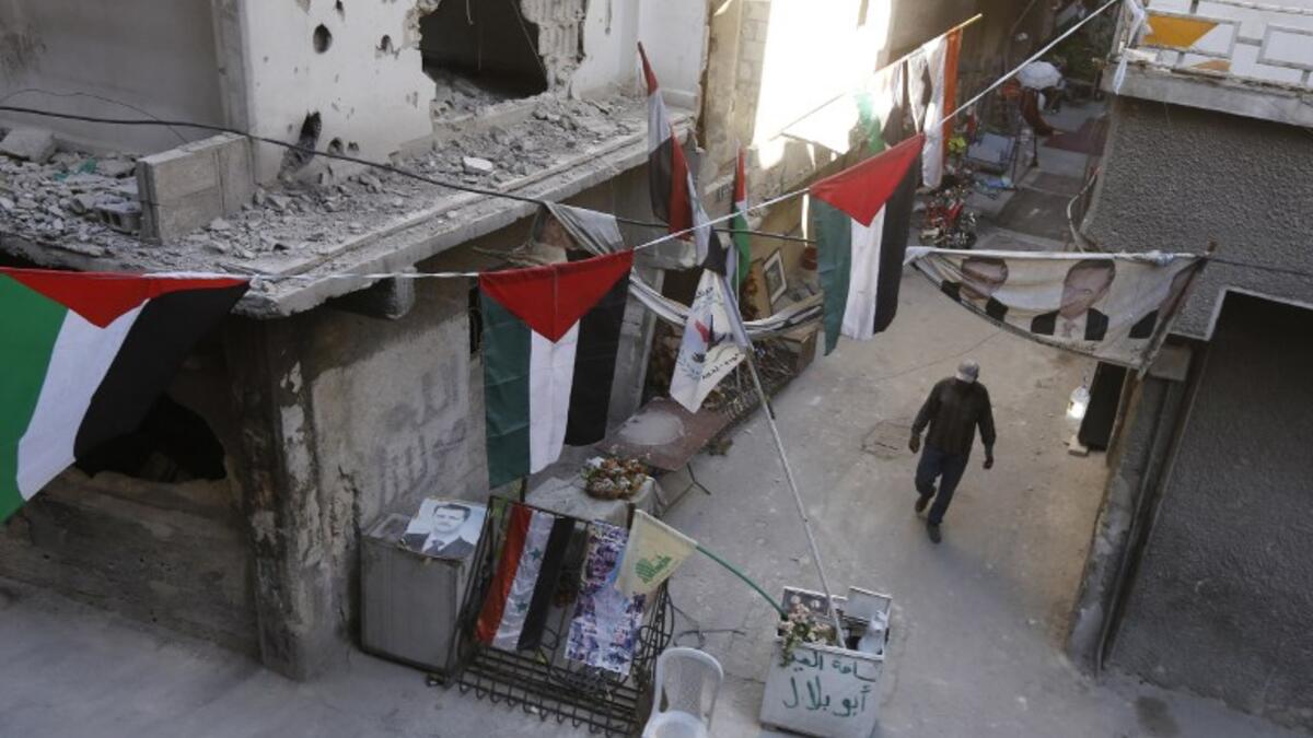 A man walks past destroyed buildings decorated with Palestinian flags in the Palestinian camp of Yarmuk southern Damascus on November 1, 2018. 
LOUAI BESHARA / AFP