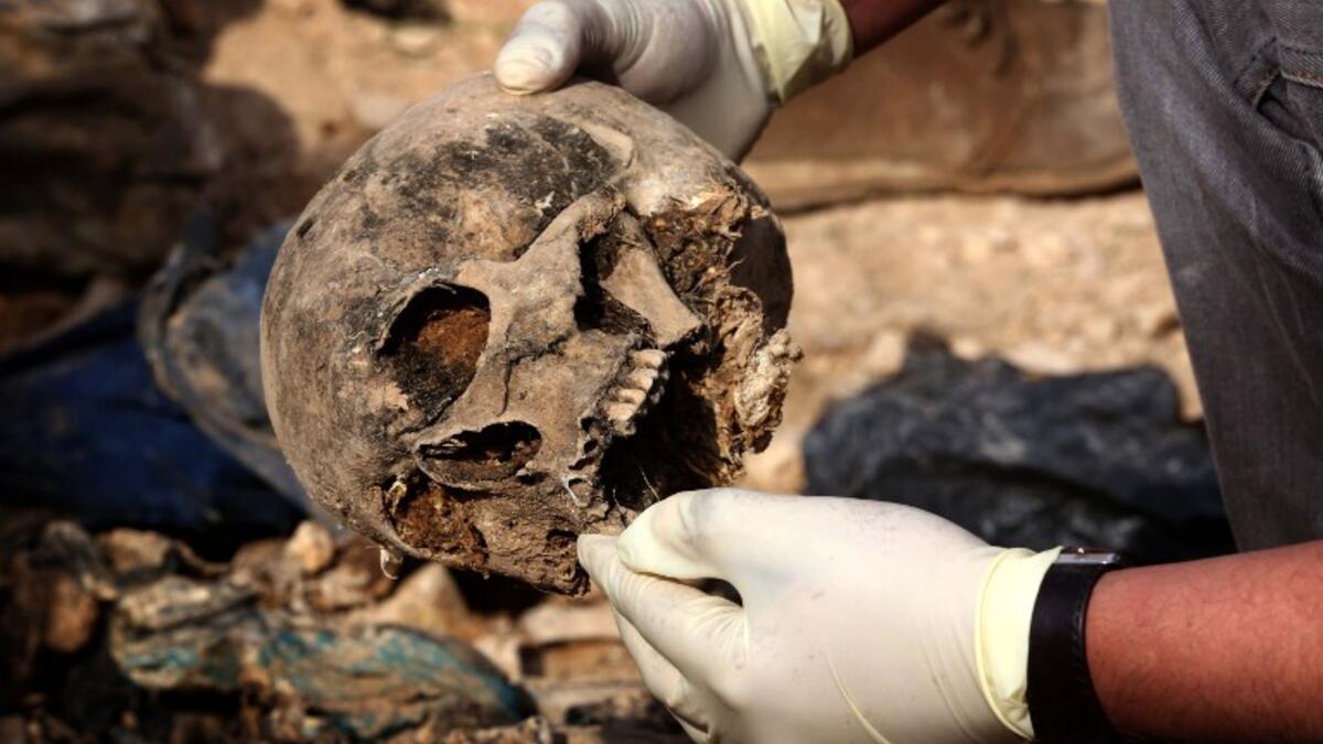 Members of the Yazidi minority search for clues, that might lead them to missing relatives in the remains of people killed by the Islamic State (IS) jihadist group. (Safin HAMED / AFP)