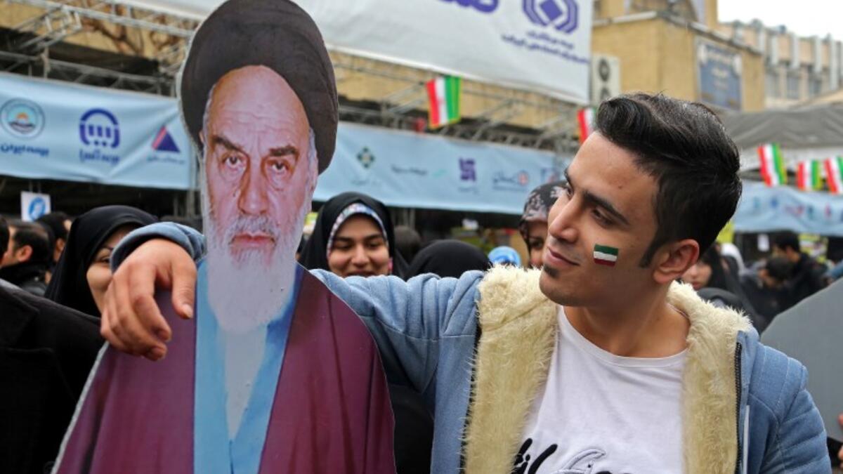 An Iranian man poses with a life-size cutout portrait of Islamic Revolution founder Ayatollah Ruhollah Khomeini during a ceremony celebrating the 40th anniversary of Islamic Revolution in the capital Tehran on February 11, 2019. 
ATTA KENARE / AFP