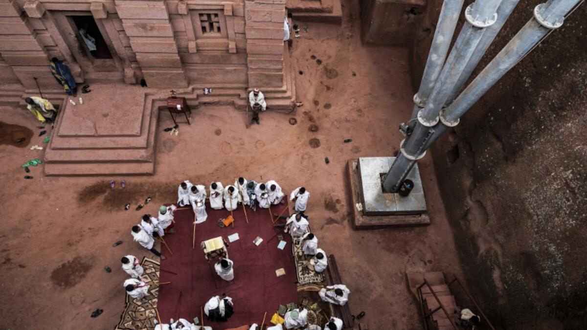 Ethiopian Orthodox devotees gather near the pillar of a shelter that protects the rock-hewn structure from erosion of the church of Saint Emmanuel in Lalibela, Ethiopia 
EDUARDO SOTERAS / AFP
